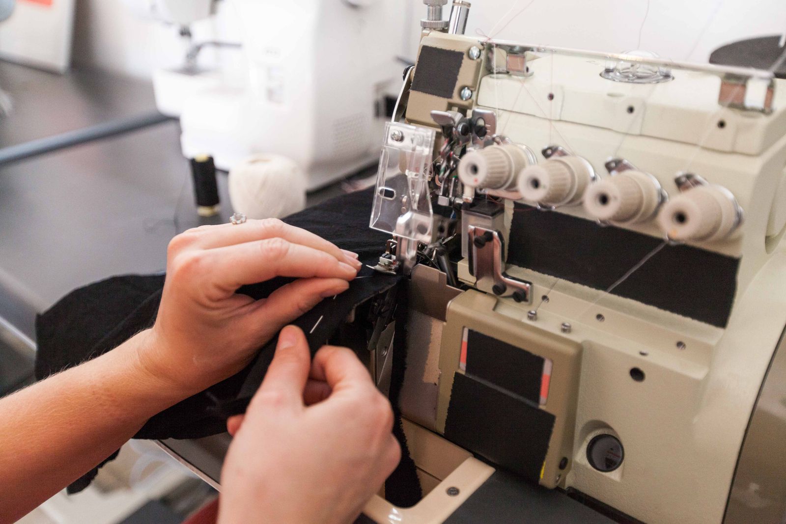 Hands guiding fabric through a serger — I Can Help Sew Flowood class