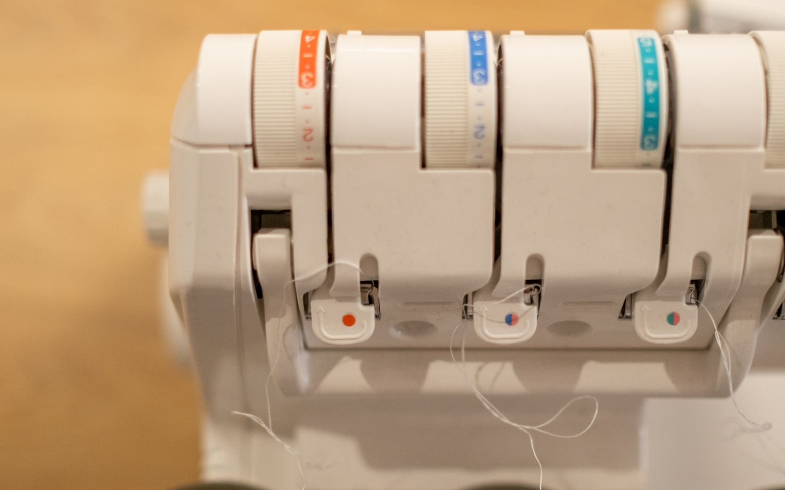 Close-up of a serger with colorful thread cones and tension dials — I Can Help Sew Flowood class